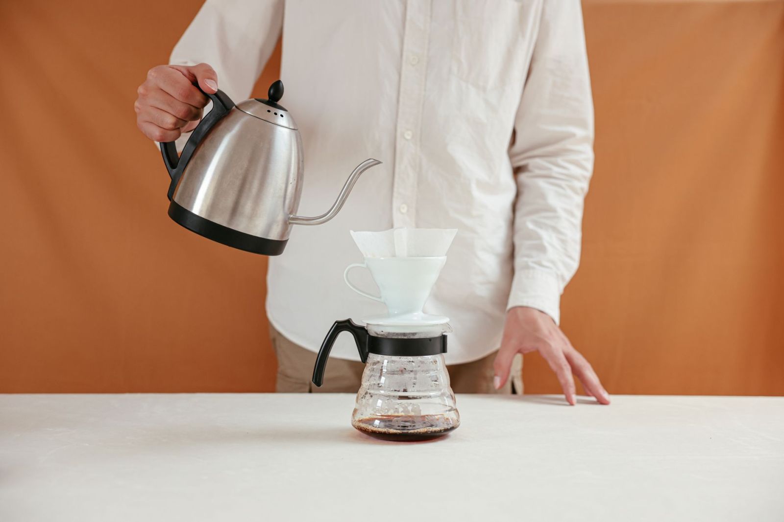 Água quente sendo despejada sobre café em filtro para preparo controlado